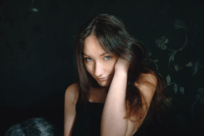 Portrait of young woman against black background