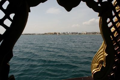 Scenic view of sea by cityscape against sky