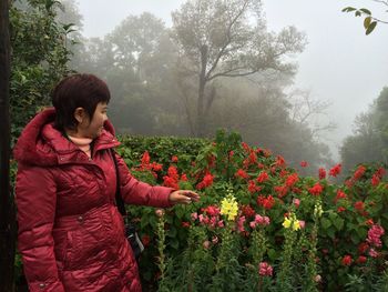 Woman standing by flowering plants during winter