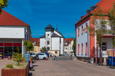 Street amidst buildings against clear blue sky