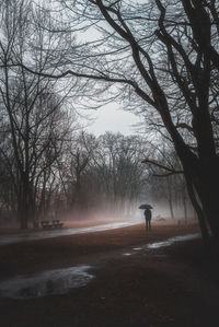 Full length of man with umbrella while on footpath