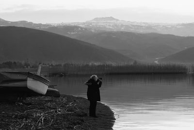 Rear view of man standing on lakeshore