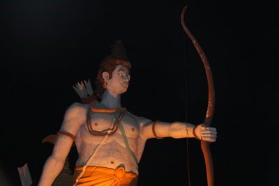 Low angle view of illuminated statue against black background