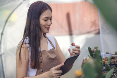 Woman looking at cactus in greenhouse garden center, asian young woman looking at small cactus