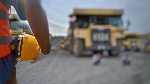 Close-up of hand holding yellow umbrella on beach