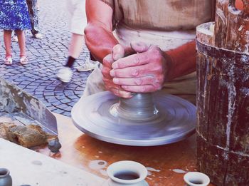 Midsection of man making pot at table