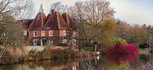Trees by lake against sky during autumn