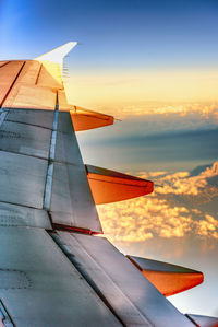 Airplane wing against sky during sunset