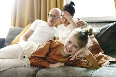 Happy daughter watching movie with unhappy parents at home