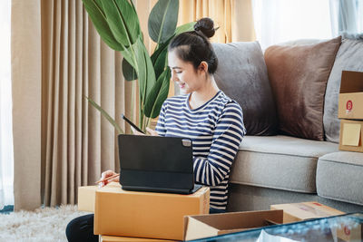 Young woman using laptop while sitting on sofa at home