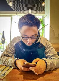 Young man using mobile phone while sitting on table