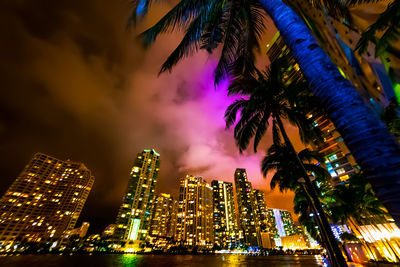 Illuminated modern buildings in city against sky at night