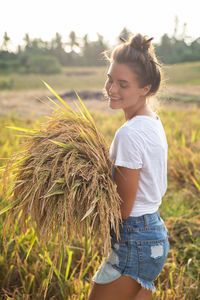 Portrait of young woman standing on hay