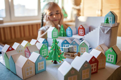 Origami advent calendar, paper craft. girl looking upon paper houses with number and paper tree