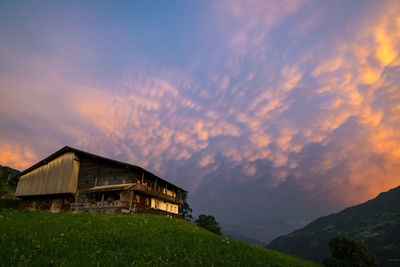 House on mountain against sky during sunset