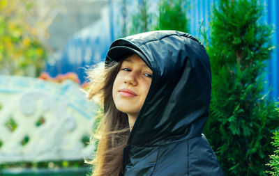 Portrait of young woman standing against trees