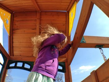 Low angle view of young woman against wooden blue wall