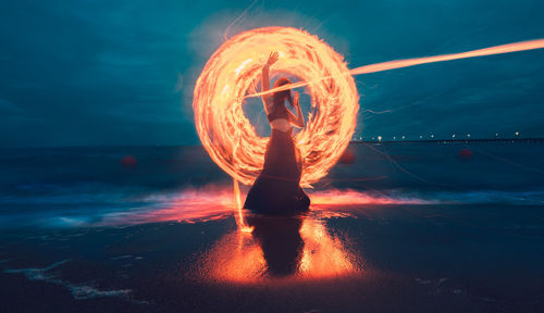 Full length of illuminated woman against sea at night