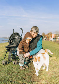 Grandfather with granddaughter and cat on and against sky