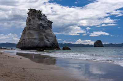 Rock formation on beach against sky