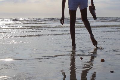 Low section of people walking on beach