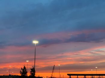 Low angle view of illuminated street light against dramatic sky