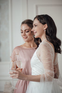 Bridesmaid and bride holding champagne flute