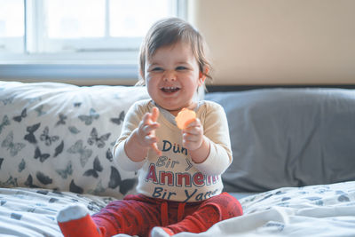 Portrait of smiling girl sitting on bed at home