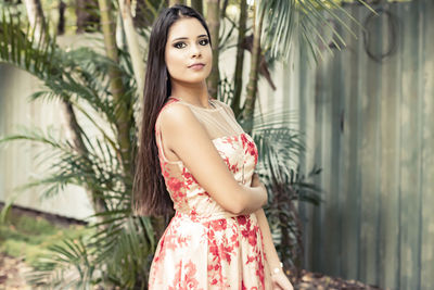 Portrait of a beautiful young woman standing against plants