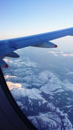 Cropped image of airplane wing over mountain