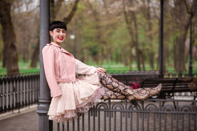 Portrait of smiling woman sitting against trees