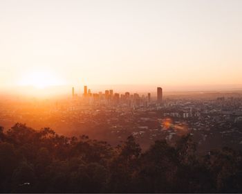 Buildings in city against clear sky during sunset