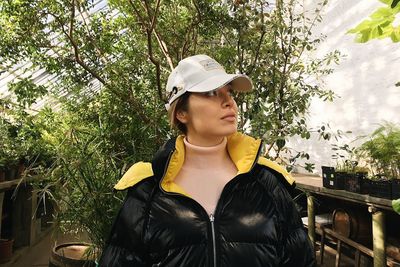 Portrait of young woman standing against plants