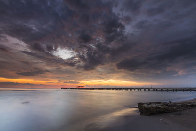 Pier on sea against cloudy sky