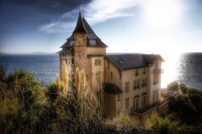 Exterior of building by sea against sky