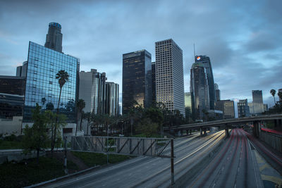 Road by buildings against sky in city