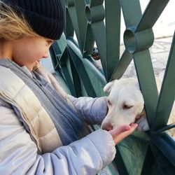 Side view of girl holding dog climbing on fence