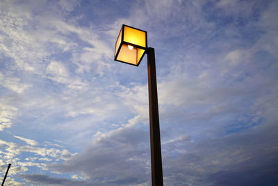 Low angle view of illuminated street light against cloudy sky