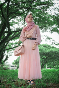 Woman standing on field against trees