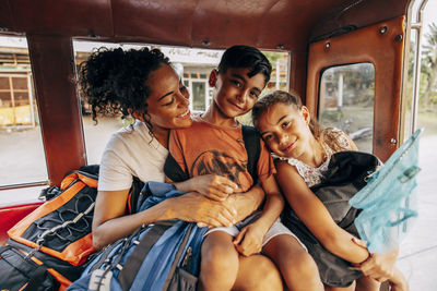 Portrait of smiling siblings traveling in tuk-tuk with mother on vacation