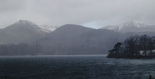 Scenic view of sea and snowcapped mountains against sky