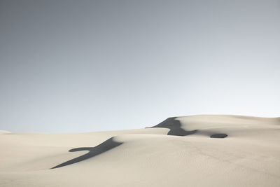 Sand dunes in desert against clear sky