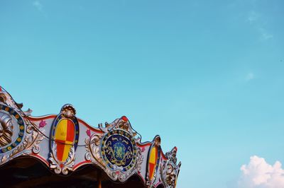 Low angle view of carousel against blue sky