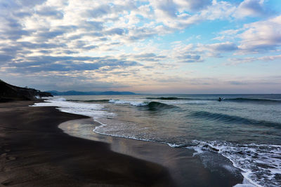 Scenic view of sea with crashing waves against dramatic sky during sunrise