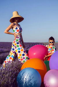 Rear view of woman with balloons against sky