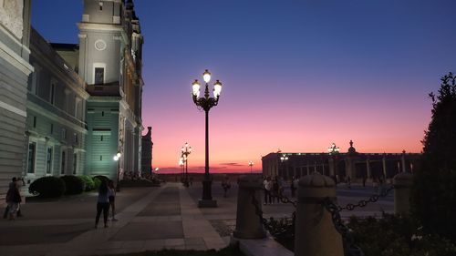 Street amidst buildings against sky at sunset