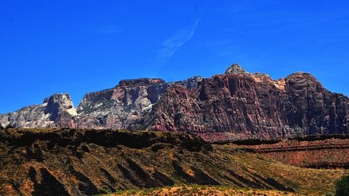 Low angle view of rocky mountain against blue sky