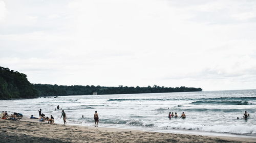 People enjoying at beach against sky