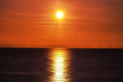 Scenic view of sea against sky during sunsunrise wind turbines llandudno 
