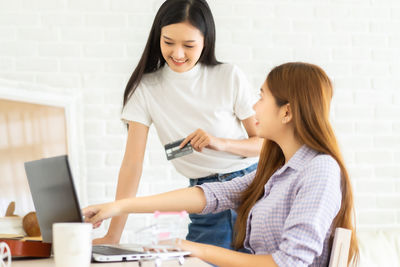 Young woman using phone while sitting on table